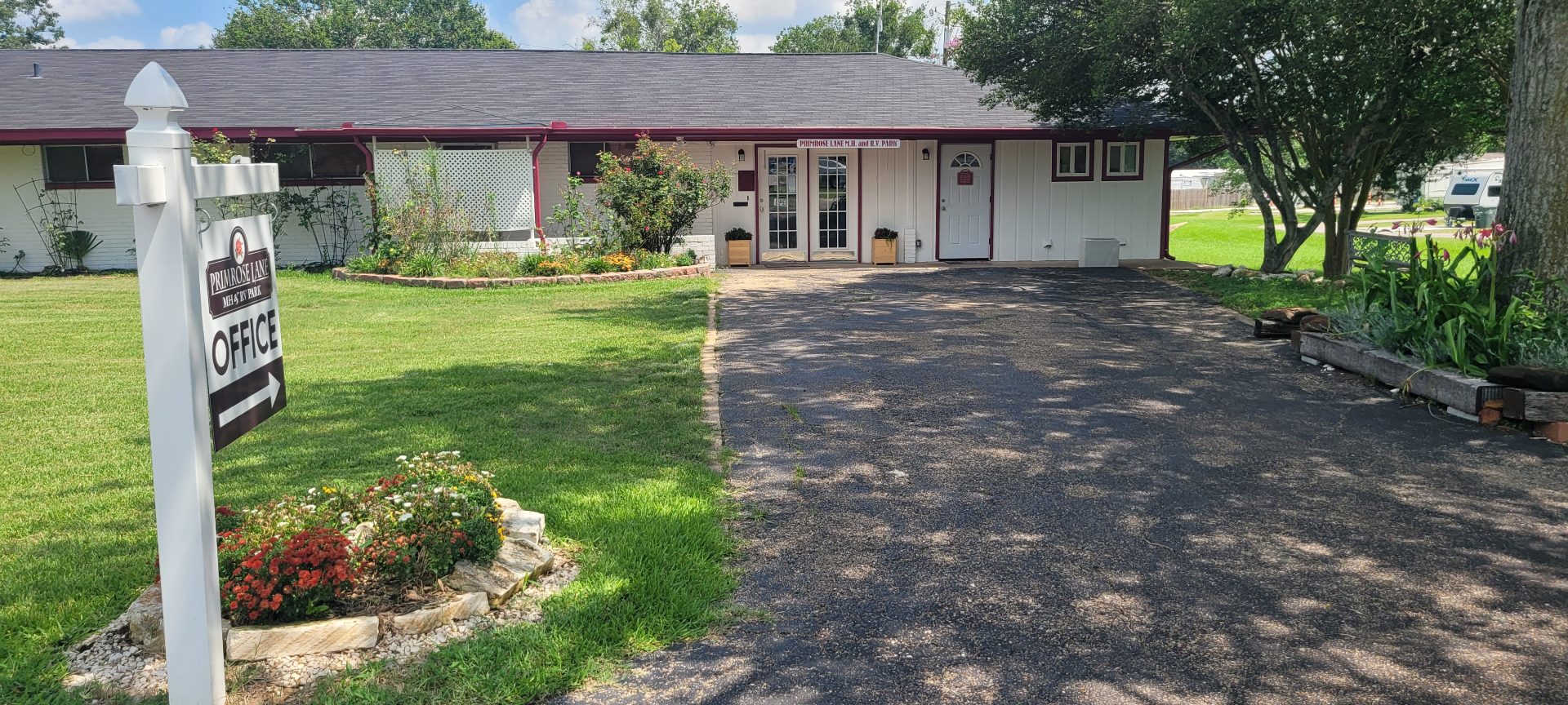 Primrose Lane RV Park office and welcome sign with flower bed